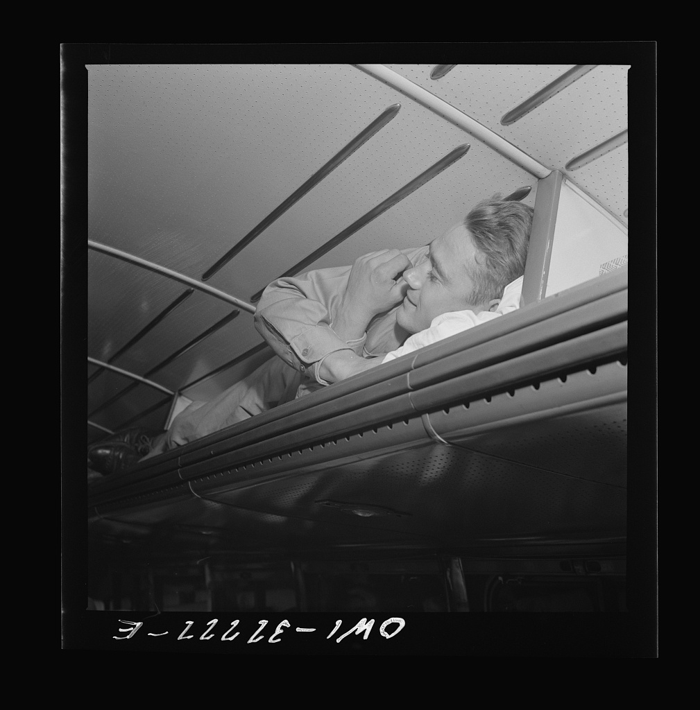 A soldier asleep in the overhead baggage rack of a Greyhound bus traveling from Cincinnati to Louisville, photographed by Esther Bubley in September 1943