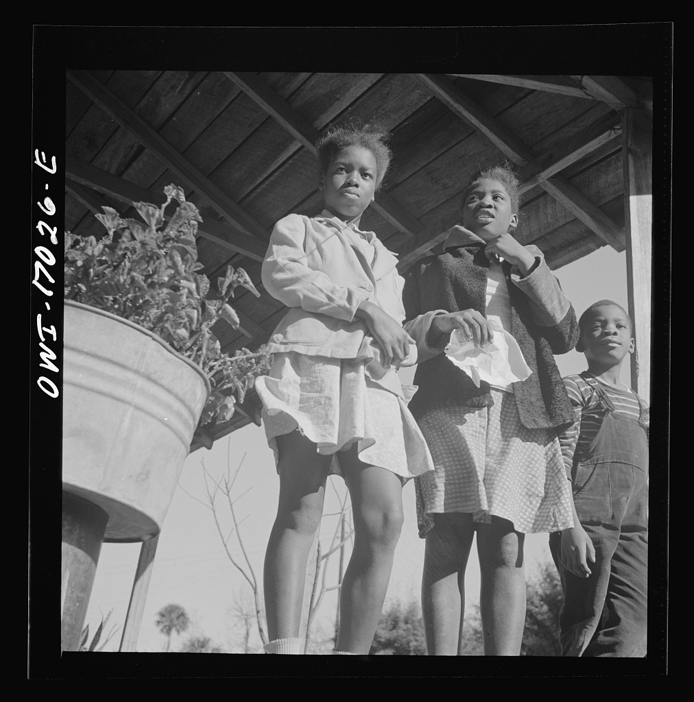 Two sisters and their brother sitting together on the front porch of the family home in Daytona Beach, Florida, photographed in February 1943 by Gordon Parks for the Office of War Information.